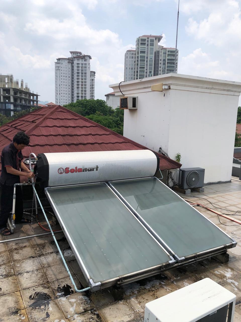 Teknisi mengerjakan service Solahart dua kolektor di atap rumah