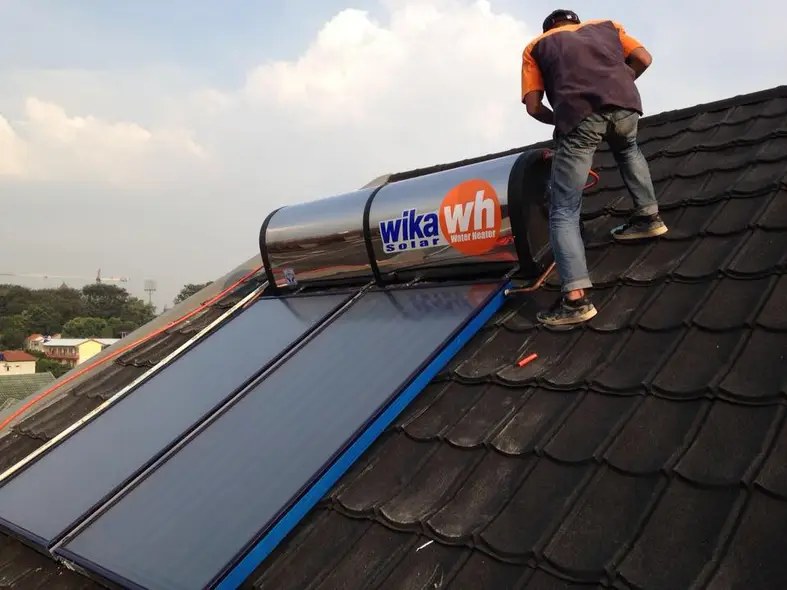 Teknisi mengerjakan service solar water heater Wika di atap rumah